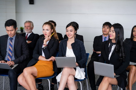 Young Asian and Caucasian audience sitting and listen to speaker in group meeting presentation at the office. Businessmen and businesswomen in training workshop. International multicultural business.の写真素材