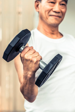 Senior man lifting dumbbell in fitness gym. Senior healthy lifestyle.の写真素材