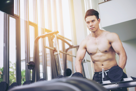 Muscular man bodybuilder in fitness gym training with dumbbells. Healthy lifestyle and bodybuilding concept.の写真素材