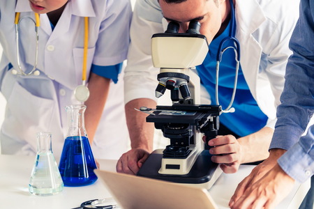 Group of scientists wearing lab coat working in laboratory while examining biochemistry sample in test tube and scientific instruments. Science technology research and development study concept.の写真素材