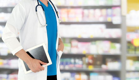 Pharmacist using tablet computer at the pharmacy. Medical healthcare and pharmaceutical staff service.の写真素材