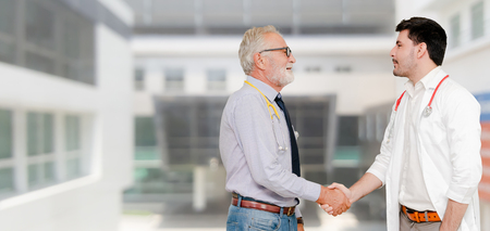 Doctor in hospital handshake with another doctor. Healthcare people teamwork and medical service concept.の写真素材