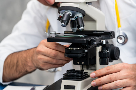 Young male doctor working using microscope in hospital laboratory. Medical and medicine technology research and development concept.の写真素材