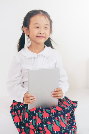 Little happy kid on white background with tablet computer. Childhood lifestyle.の写真素材