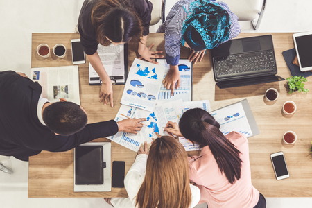 Top view of businessman executive in group meeting with other businessmen and businesswomen in modern office with laptop computer, coffee and document on table. People corporate business team concept.の写真素材