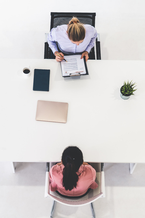 Two young business women in meeting at office table for job application and business agreement. Recruitment and human resources concept.の写真素材