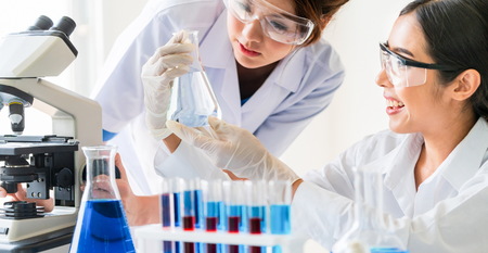 Group of scientists wearing lab coat working in laboratory while examining biochemistry sample in test tube and scientific instruments. Science technology research and development study concept.の写真素材