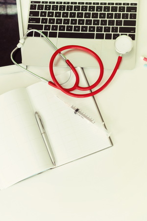 Medical healthcare backgrounds flat lay objects with copy space. Doctor stethoscope, medicine, laptop computer and notebook on white office table.の写真素材