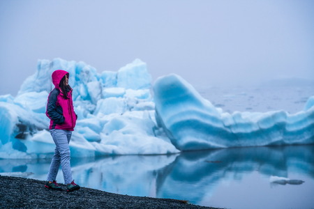 Woman traveler travels to Jokulsarlon beautiful glacial lagoon in Iceland. Jokulsarlon is a famous destination in Vatnajokull National Park, southeast Iceland, Europe. Cold winter ice nature.の写真素材