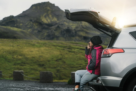 Woman tourist travel by SUV car for road trip in Iceland. The traveler parking the car and enjoy beautiful scenery of mountain landscape in the background. Discovery and exploration.の写真素材