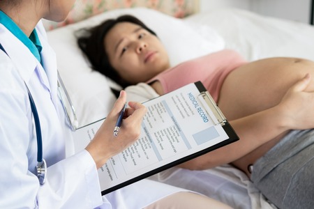 Happy pregnant woman visit gynecologist doctor at hospital or medical clinic for pregnancy consultant. Doctor examine pregnant belly for baby and mother healthcare check up. Gynecology concept.の写真素材