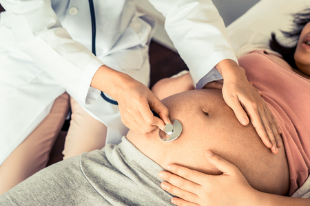 Happy pregnant woman visit gynecologist doctor at hospital or medical clinic for pregnancy consultant. Doctor examine pregnant belly for baby and mother healthcare check up. Gynecology concept.の写真素材