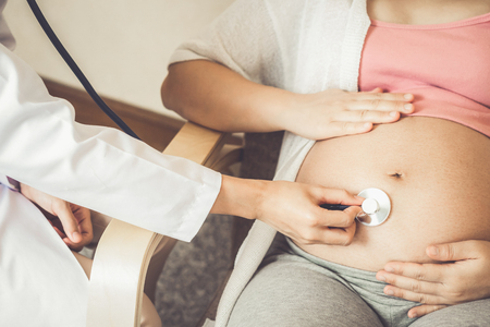 Happy pregnant woman visit gynecologist doctor at hospital or medical clinic for pregnancy consultant. Doctor examine pregnant belly for baby and mother healthcare check up. Gynecology concept.の写真素材