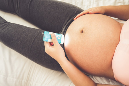 Pregnant woman feeling happy at home while taking care of her child. The young expecting mother...