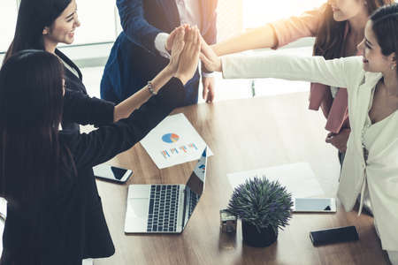Businesswomen joining hands in group meeting at modern office room showing teamwork, support and unity in work and business. Female power and femininity concept.の写真素材