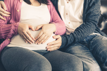 Pregnant couple of husband and wife feels love and relax at home. Young expecting woman holds baby...