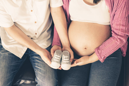 Pregnant couple of husband and wife feels love and relax at home. Young expecting woman holds baby...
