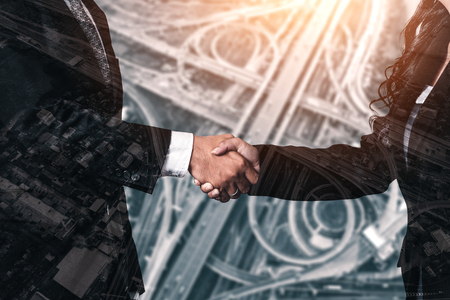 Double exposure image of business people handshake on city office building in background showing partnership success of business deal. Concept of corporate teamwork, trust partner and work agreement.の写真素材