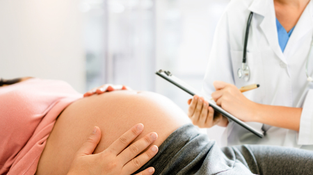 Happy pregnant woman visit gynecologist doctor at hospital or medical clinic for pregnancy consultant. Doctor examine pregnant belly for baby and mother healthcare check up. Gynecology concept.の写真素材
