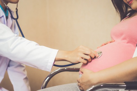 Happy pregnant woman visit gynecologist doctor at hospital or medical clinic for pregnancy consultant. Doctor examine pregnant belly for baby and mother healthcare check up. Gynecology concept.の写真素材