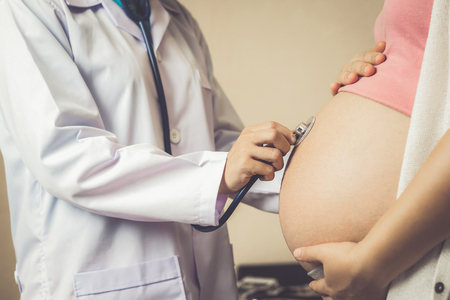 Happy pregnant woman visit gynecologist doctor at hospital or medical clinic for pregnancy consultant. Doctor examine pregnant belly for baby and mother healthcare check up. Gynecology concept.の写真素材