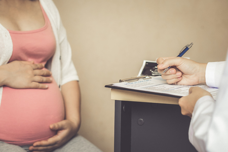 Happy pregnant woman visit gynecologist doctor at hospital or medical clinic for pregnancy consultant. Doctor examine pregnant belly for baby and mother healthcare check up. Gynecology concept.の写真素材