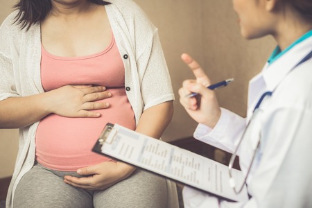 Happy pregnant woman visit gynecologist doctor at hospital or medical clinic for pregnancy consultant. Doctor examine pregnant belly for baby and mother healthcare check up. Gynecology concept.の写真素材