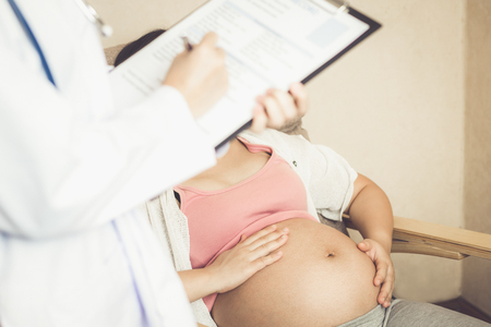 Happy pregnant woman visit gynecologist doctor at hospital or medical clinic for pregnancy consultant. Doctor examine pregnant belly for baby and mother healthcare check up. Gynecology concept.の写真素材