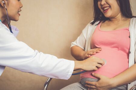 Happy pregnant woman visit gynecologist doctor at hospital or medical clinic for pregnancy consultant. Doctor examine pregnant belly for baby and mother healthcare check up. Gynecology concept.の写真素材
