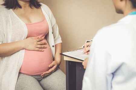Happy pregnant woman visit gynecologist doctor at hospital or medical clinic for pregnancy consultant. Doctor examine pregnant belly for baby and mother healthcare check up. Gynecology concept.の写真素材