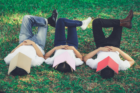 Funny students sleeping with books covering their face. Lazy and relaxation concept.