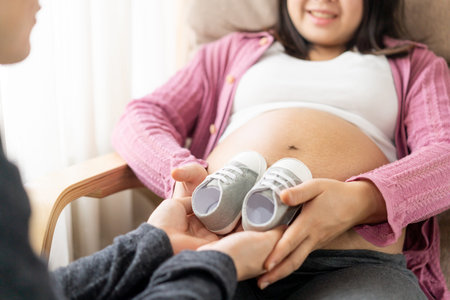 Pregnant couple of husband and wife feels love and relax at home. Young expecting woman holds baby...