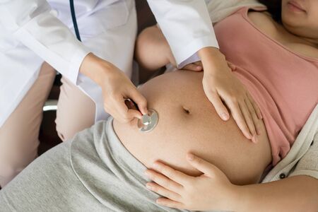 Happy pregnant woman visit gynecologist doctor at hospital or medical clinic for pregnancy consultant. Doctor examine pregnant belly for baby and mother healthcare check up. Gynecology concept.の写真素材