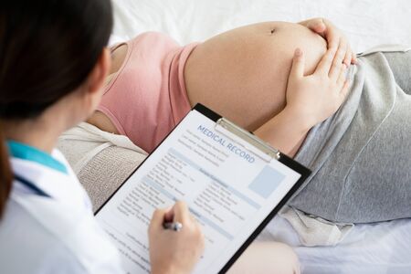 Happy pregnant woman visit gynecologist doctor at hospital or medical clinic for pregnancy consultant. Doctor examine pregnant belly for baby and mother healthcare check up. Gynecology concept.の写真素材