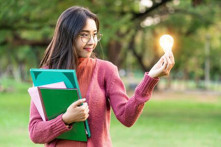 Creative young woman hold shinning light bulb. Concept of knowledge, intelligence and inspiration.の写真素材