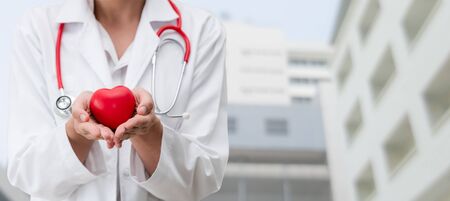 Doctor holding a red heart at hospital office. Medical health care and doctor staff service concept.の写真素材
