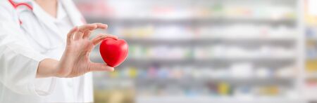 Doctor holding a red heart at hospital office. Medical health care and doctor staff service concept.の写真素材
