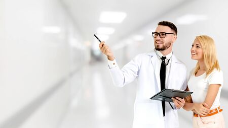 Doctor with patient pointing at empty copy space for your text. The happy patient is listening to explanation from the doctor. Concept of medical healthcare and doctor staff service.の写真素材