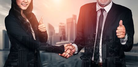 Double exposure image of business people handshake on city office building in background showing partnership success of business deal. Concept of corporate teamwork, trust partner and work agreement.の写真素材