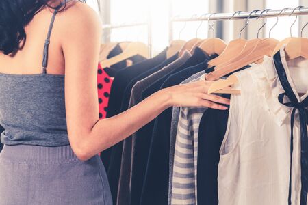 Beautiful woman shopping for clothes at retail apparel shop in the shopping mall. Modern trade lifestyle.の写真素材
