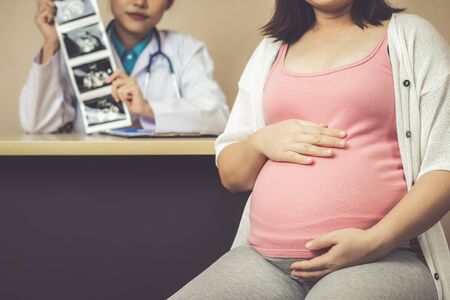 Happy pregnant woman visit gynecologist doctor at hospital or medical clinic for pregnancy consultant. Doctor examine pregnant belly for baby and mother healthcare check up. Gynecology concept.の写真素材