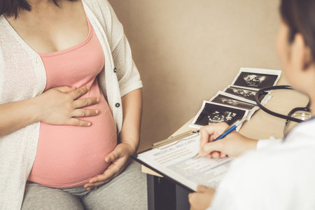 Happy pregnant woman visit gynecologist doctor at hospital or medical clinic for pregnancy consultant. Doctor examine pregnant belly for baby and mother healthcare check up. Gynecology concept.の写真素材