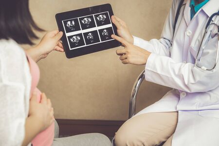 Happy pregnant woman visit gynecologist doctor at hospital or medical clinic for pregnancy consultant. Doctor examine pregnant belly for baby and mother healthcare check up. Gynecology concept.の写真素材