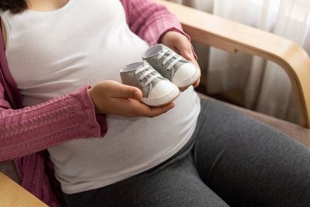 Pregnant woman feeling happy at home while taking care of her child. The young expecting mother...