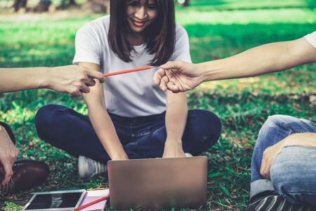 Team of young students studying in a group project in the park of university or school. Happy learning, community teamwork and youth friendship concept.の写真素材