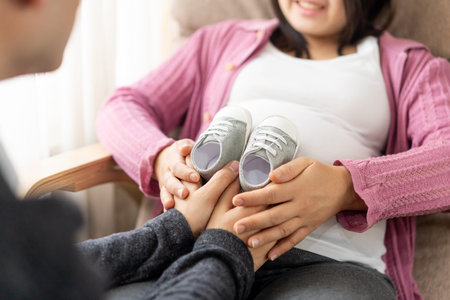 Pregnant couple of husband and wife feels love and relax at home. Young expecting woman holds baby...