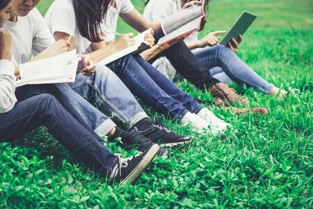 Team of young students studying in a group project in the park of university or school. Happy learning, community teamwork and youth friendship concept.の写真素材