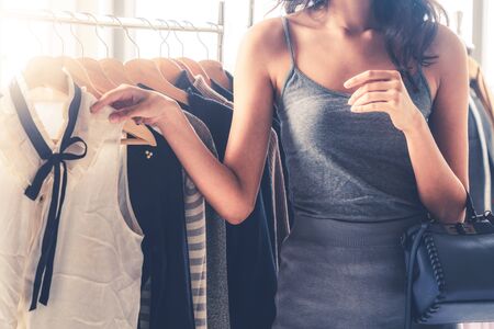 Beautiful woman shopping for clothes at retail apparel shop in the shopping mall. Modern trade lifestyle.の写真素材
