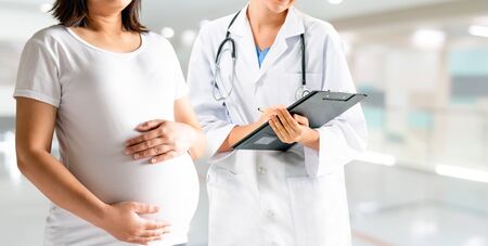 Happy pregnant woman visit gynecologist doctor at hospital or medical clinic for pregnancy consultant. Doctor examine pregnant belly for baby and mother healthcare check up. Gynecology concept.の写真素材