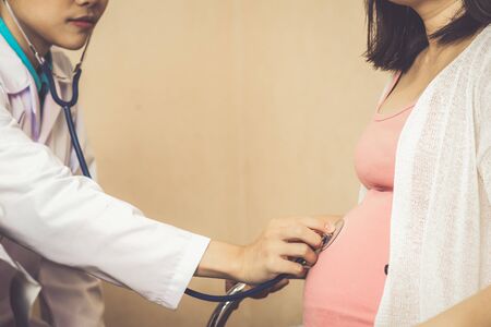 Happy pregnant woman visit gynecologist doctor at hospital or medical clinic for pregnancy consultant. Doctor examine pregnant belly for baby and mother healthcare check up. Gynecology concept.の写真素材